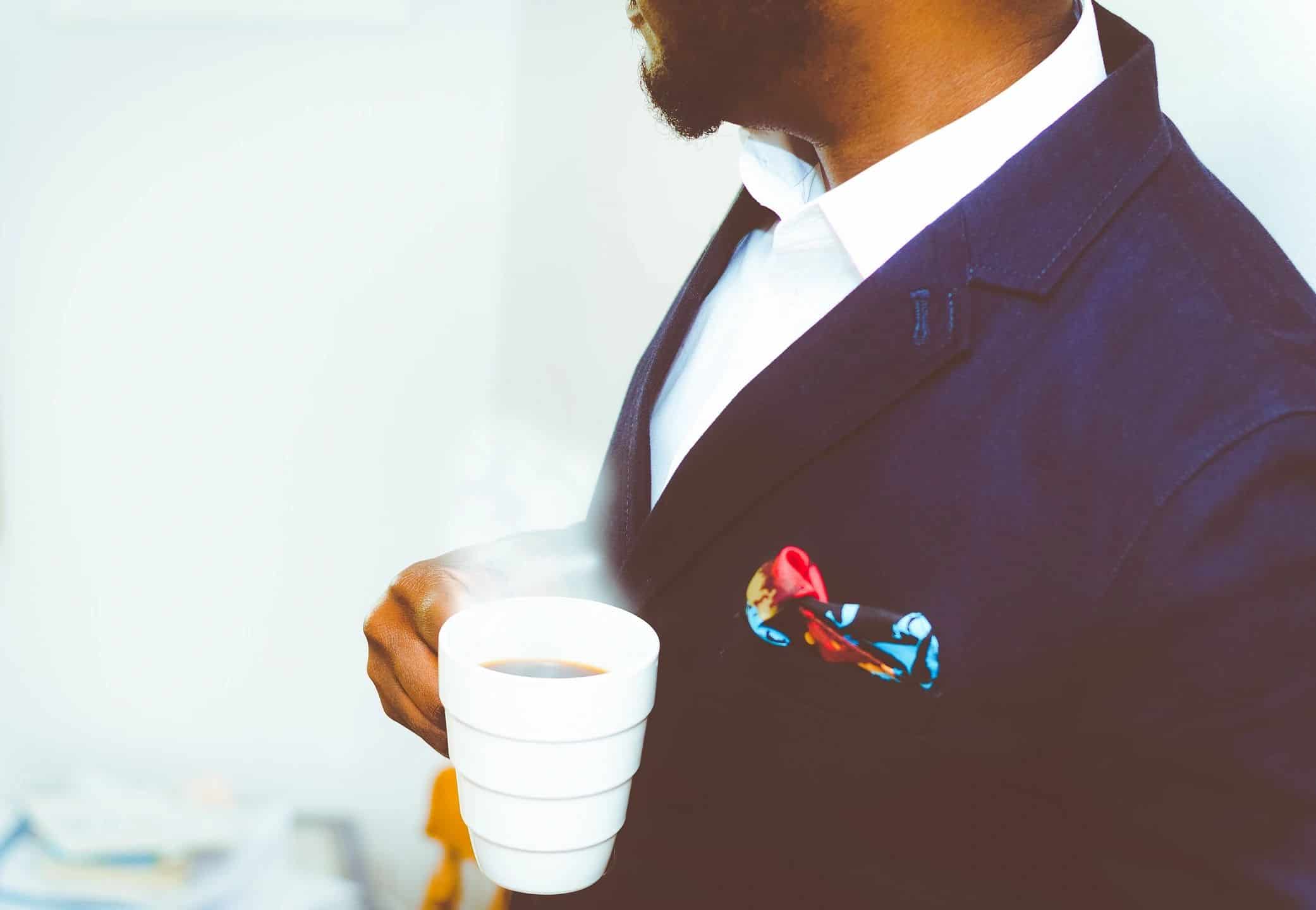 Business attorney in a navy suit holding a cup of coffee