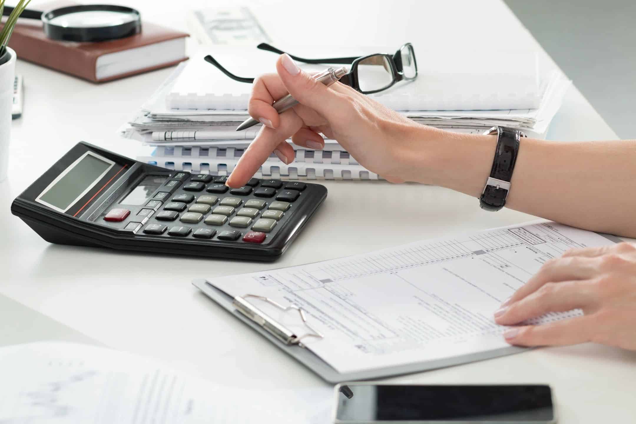 Accountant using a calculator to review past due invoices and payment records
