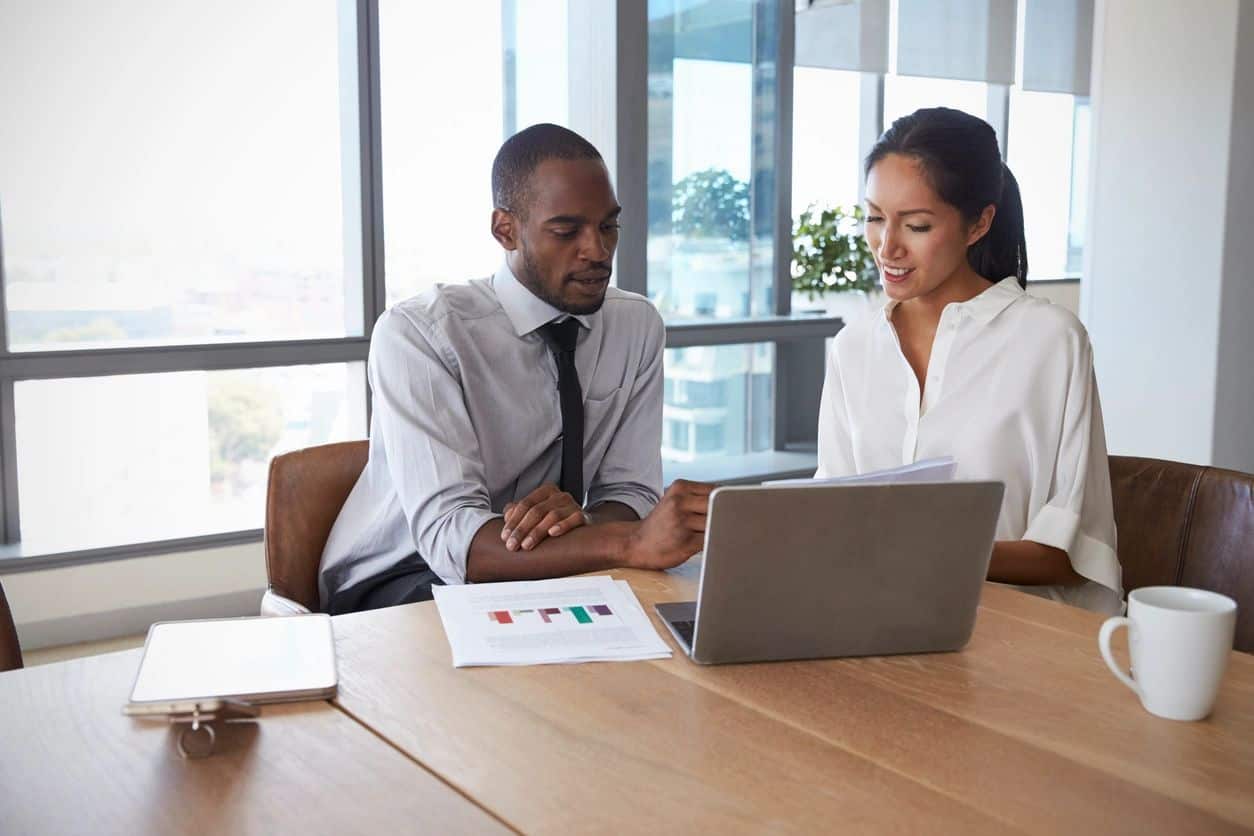 Two business professionals reviewing delinquent accounts receivable on a laptop