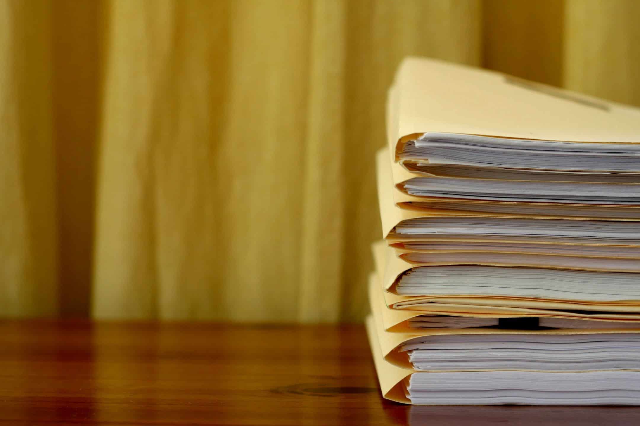 Stack of manila file folders holding commercial collection records