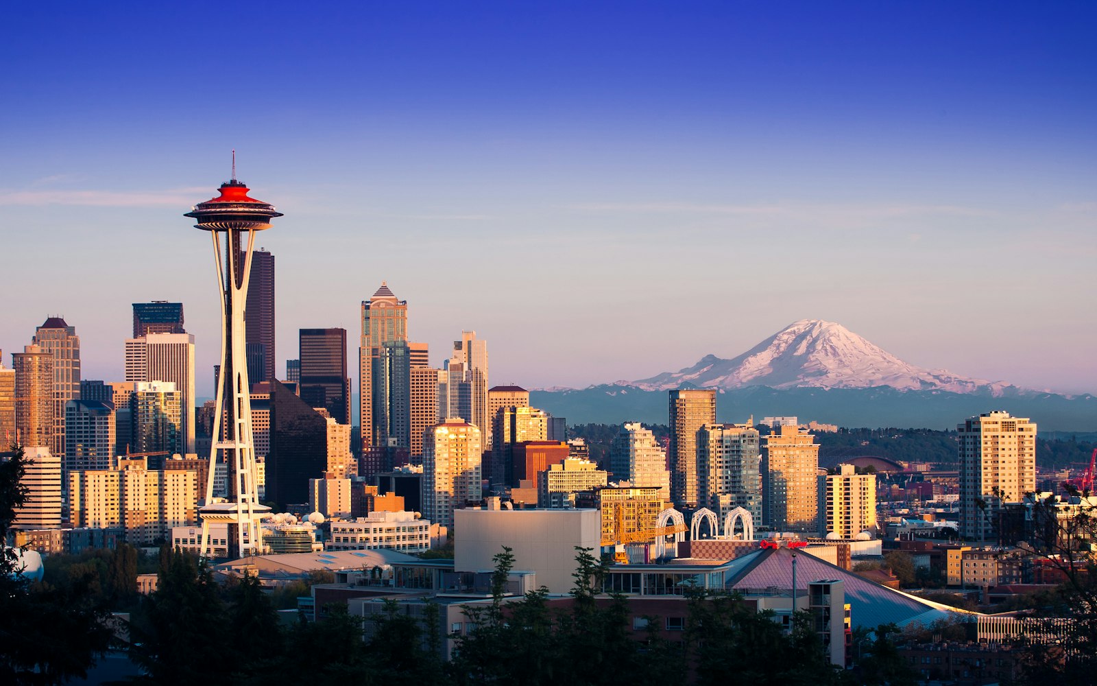 Seattle skyline at golden hour with the Space Needle on the left and Mount Rainier rising behind downtown, the Washington market where creditors pursue unpaid commercial invoices