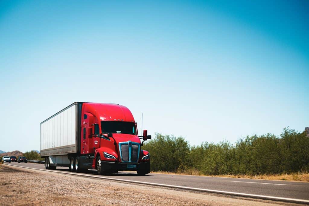 Red semi truck hauling a trailer on a US highway, the kind of load whose unpaid freight invoice The Guy That Gets You Paid collects for carriers and brokers
