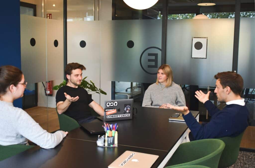 Software company finance and sales team meeting around a table with laptops, discussing unpaid SaaS invoices and collections